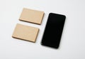 Two stack of craft business cards and black smartphone on white background. Horizontal