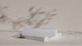 Two stacked rectangular platforms made of white material sit on light beige surface. Blurred shadows of leaves cast from an unseen