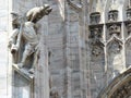 Statues of a musician with a dog of the cathedral of Milan in Italy.