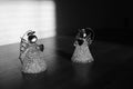 Two statues of small angels on the table. The fight of good and evil. Light with shadow. Black and white photo