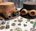 two steampunk hats, with goggles and gears, magnifying glass