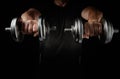 Two steel typesetting dumbbells in male hands, sports backdrop