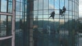 Two steeplejacks are cleaning the windows of the business center