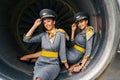 Two stewardesses posing for the camera seated in the aeroengine