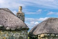 Two stone built cottages with thatched roofs, with a chimney stack and chimney