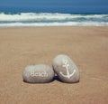 Two stone pebbles with the word beach and anchor sign over sandy beach and sea horizon Royalty Free Stock Photo