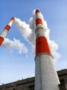 Two stone pipes of a power plant releasing steam from generating electricity against a blue sky Royalty Free Stock Photo