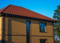 Two-storey house with tall vertical window on the stairwell and show-guard on the metal tiled roof