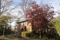 A two story brick house with green window shutters and an arched door