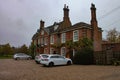 Two-story private house with windows with white bars and cars parking in the yard in London, UK