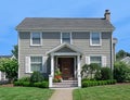 Two story clapboard house with shrubbery and front lawn in summer