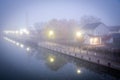 Two story house with American flag in mist foggy early morning along historic Erie Canal with yellow pole lighting, colorful fall Royalty Free Stock Photo