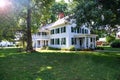 Two-story house with a balcony and a veranda in a traditional American style covered with siding. Shrubs and trimmed lawn in the Royalty Free Stock Photo