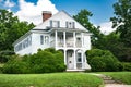 Two-story house in a traditional American style covered with siding. Shrubs and trimmed lawn on the frontyard