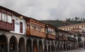 Two story shops with stone archways at street level and ornate wood patios in Cusco, Peru