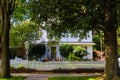 Two story white wood house with picket fence pumpkins and an American flag flanked by two large trees Royalty Free Stock Photo