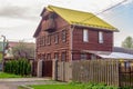 A two-story wooden brown log house, with an attic and a yellow tiled roof.