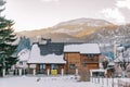 Two-story wooden cottage in a snowy village at the foot of the mountains