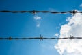 Two strands of barbed wire with blue sky and clouds in the background Royalty Free Stock Photo