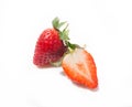 Two strawberries, one half and the whole one behind it is isolated on a white background Royalty Free Stock Photo