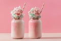 Two strawberry milkshakes topped with a cotton candy