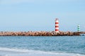 Two striped lighthouses stand on the beach in the city of Faro in Portugal. Little waves in the ocean on a sunny day . Royalty Free Stock Photo