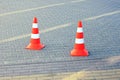 two striped plastic limiter cones stand on a gray sidewalk