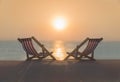 Two striped red-white sunbeds at sandy tropical sunset ocean beach.