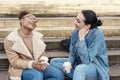 two student women in denim jacket is talking to each other, on phone, laughing, drinking coffee on stairs in city Royalty Free Stock Photo