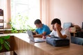 Two students collaborating on projects at school, using laptops and tablets while taking notes. Focused on their academics. Royalty Free Stock Photo