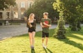 Two students, female and male, cheerfully walk in the university park holding their notebooks. Couple of students casually walk in Royalty Free Stock Photo