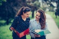 Two students learning reading a notebook and commenting in the street