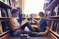 Studying together, but separately. Two students reading separate textbooks in the library. Royalty Free Stock Photo