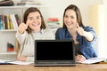 Two students showing a blank laptop screen