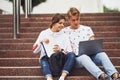 Two students sitting on stairs outdoors with laptop at daytime Royalty Free Stock Photo