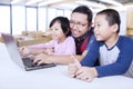 Two students using laptop in class with teacher Royalty Free Stock Photo