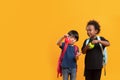 Two students 3 years, Asian and Black child boy of different nationalities carry a school bag and stand playing with apples