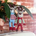 Children toys. Two stylish amigurumi deers in striped sweaters, scarf and butterfly tie standing near flowerpot