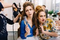 Two stylish astonished models in beauty salon during preparation to party. Fashionable coiffure, hairdresser service Royalty Free Stock Photo