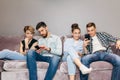 Two stylish couples are staring at phones while resting on the couch indoors Royalty Free Stock Photo