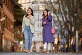 Two stylish female friends talking while walking together outdoors. Royalty Free Stock Photo