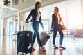 Two stylish female travelers walking with their luggage in airport