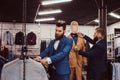 Two stylish shop assistants elegantly dressed working in a menswear store.