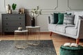 stylish small coffee tables with marble tops in front of elegant grey couch with emerald pillows