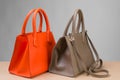 Two stylish women bags, orange and brown, on gray background, concept