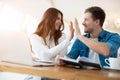 Two successful colleagues brunette woman and handsome man giving each other high five while working in laptop during lunch break Royalty Free Stock Photo