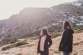 Two successful hiker woman friends enjoy the view on mountain peak. Happy backpackers in nature