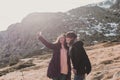 Two successful hiker woman friends enjoy the view on mountain peak. Happy backpackers in nature taking pictures with mobile phone Royalty Free Stock Photo