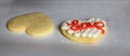 Two sugar cookies on parchment paper covered cookie sheet, one decorated and one not