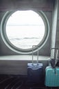 Two suitcases for traveling in front of the round porthole of the ship, the concept of leisure or business trip Royalty Free Stock Photo